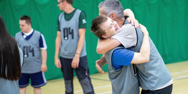 A young man in sports clothes hugs teammate 