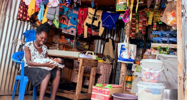 Evaline sitting in her shop surrounded by clothes she's made