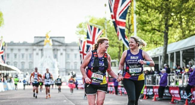 Two female runners running down the Mall in London in front of Buckingham Palace