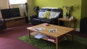Lounge with brown carpet and lime green coloured walls, an oak style coffee tablet and brown sofa with TV and stand next to it