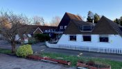 Chipstead front exterior with triangle shaped tiled roof and a white picket fence surrounding it 
