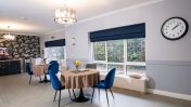 Dining Room with windows with blue blinds and round dining tables with blue dining chairs and diamante hanging lampshades