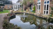 A large pond in the garden with a water feature in the middle of it