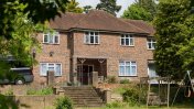 A brown bricked house with a thatched roof and front garden with steps leading up to the house 