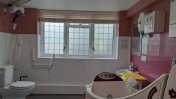An accessible bathroom with panelled windows and dark pink walls