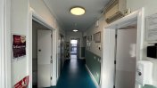 Corridor with smooth blue floor and doors to rooms either side with bright dome lights on the ceiling 
