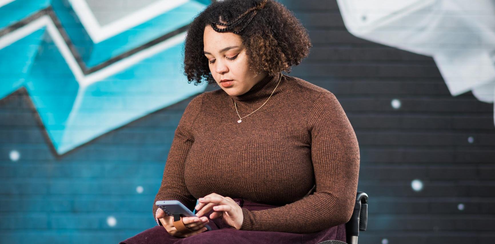 Cassie in her wheelchair looking at her phone