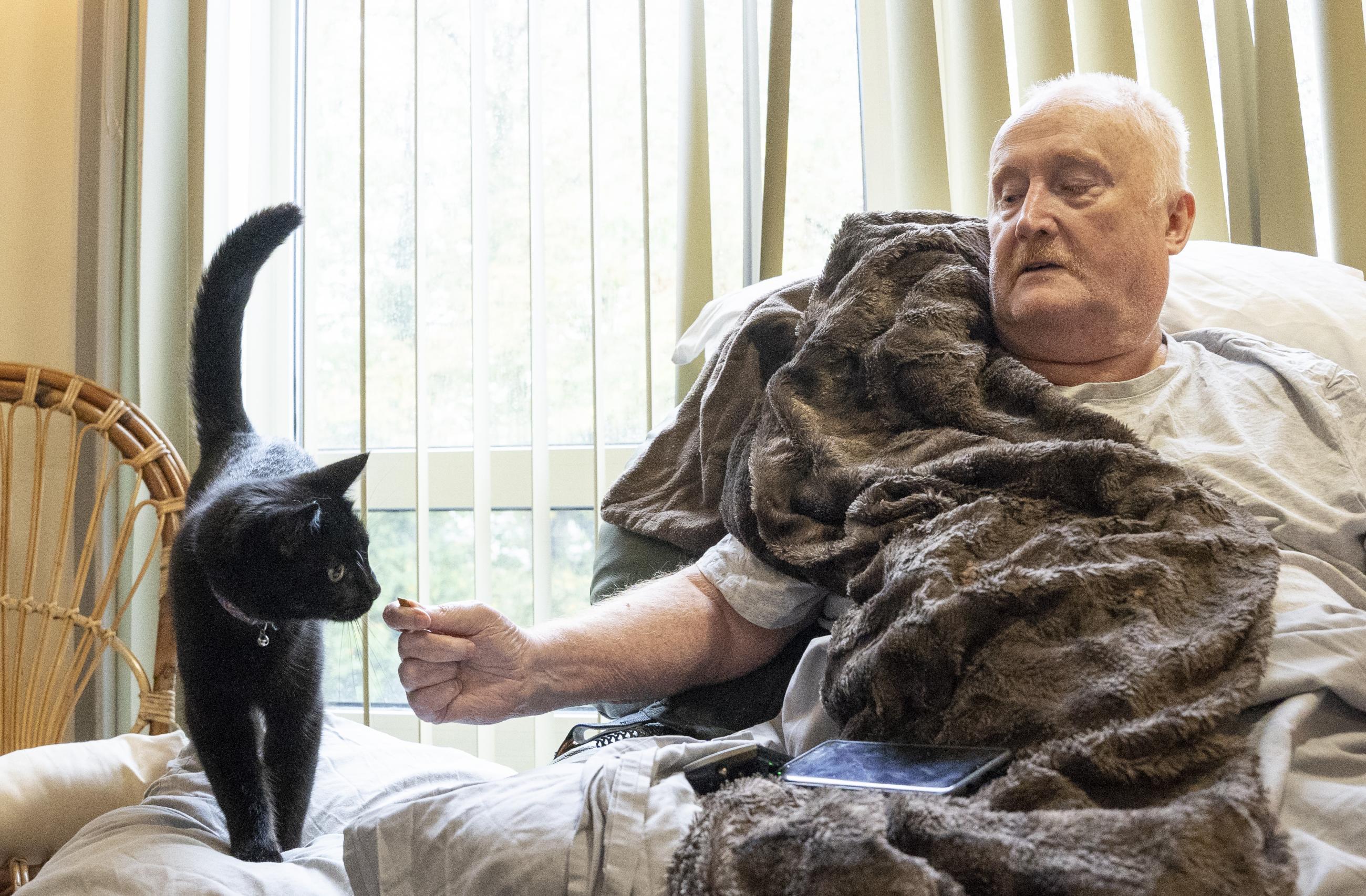 A man in a chair with a black cat next to him