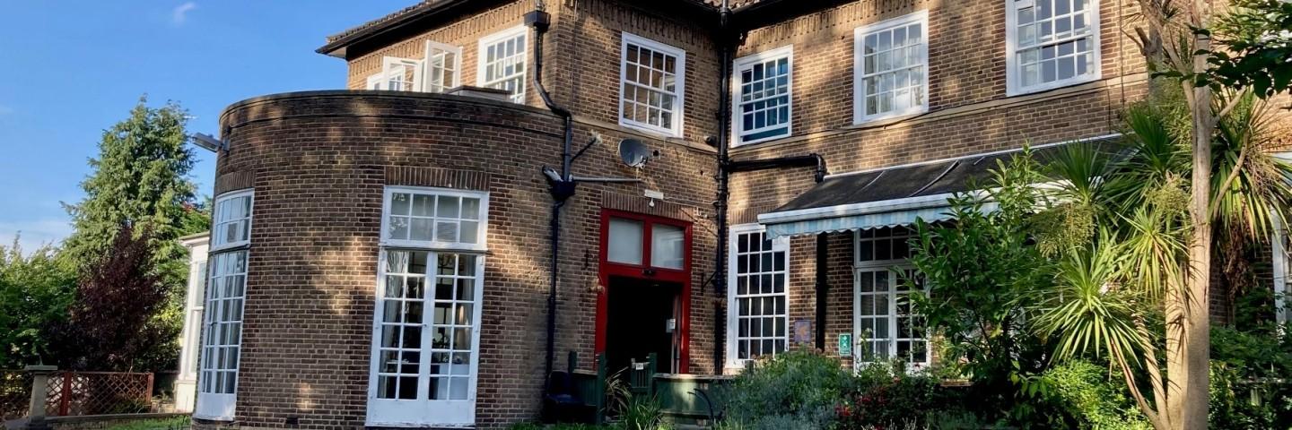 An exterior shot of a bricked house with the sun shining on it
