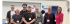 The AT team stood together smiling in front of conference boards 