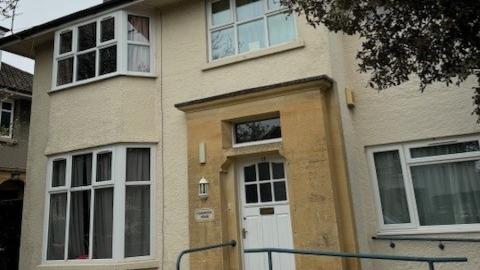 The outside of a cream two storey house with a white panelled front door with an accessible ramp in front of it 