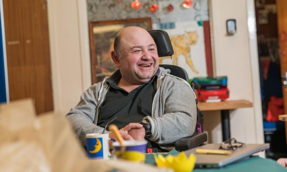 A man in a wheelchair looking to the right laughing