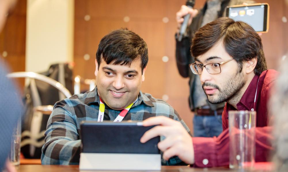 Anil, a Can Doer, and Alper, Partnerships Coordinator, at the Can Do Steering Group looking at a iPad