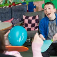 A boy laughs while playing a game at one of the Leonard Cheshire services