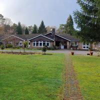 exterior view of Hydon Hill a bungalow style building with a big front lawn in front of it and lots of greenery