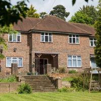 A brown bricked house with a thatched roof with 5 windows and a door entrance with a garden in front of it and steps leading up