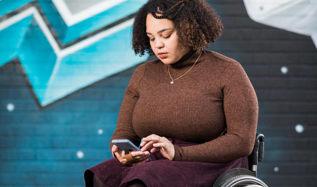 Cassie in her wheelchair looking at her phone